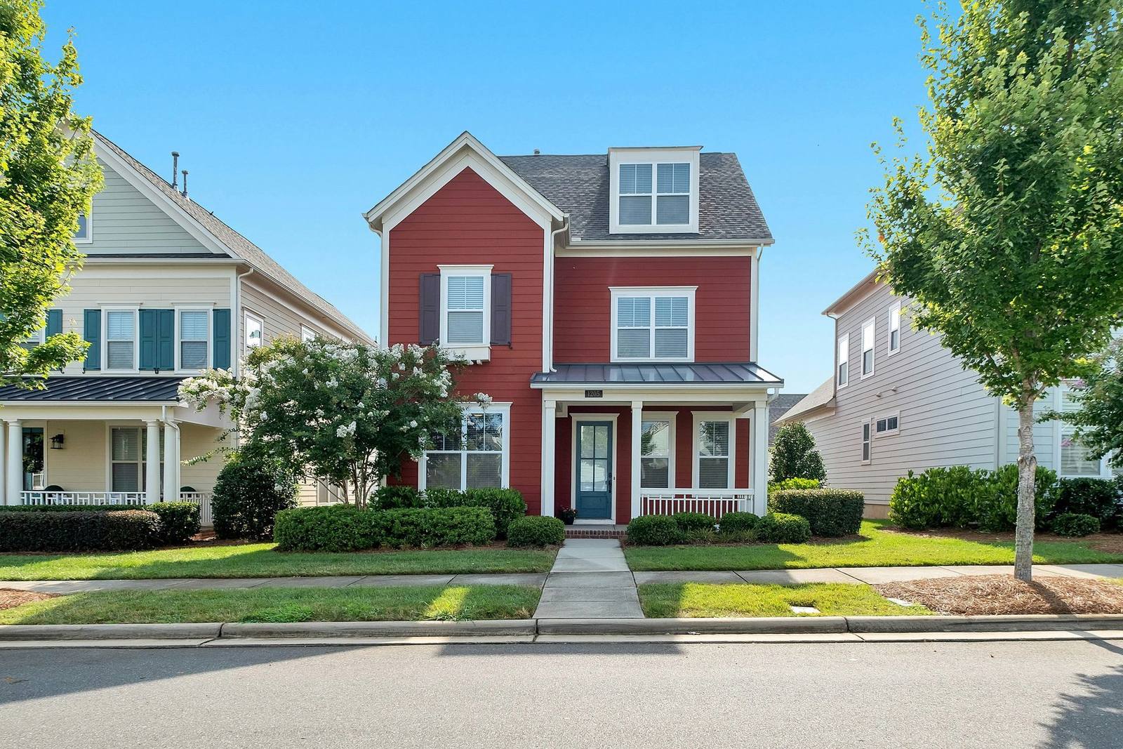 Red colonial-style home exterior among mature trees